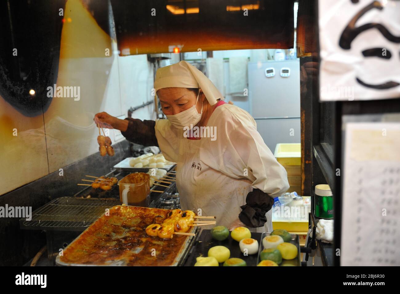 Une femme à la rue principale de Gion est de griller de la nourriture de rue à vendre. Banque D'Images