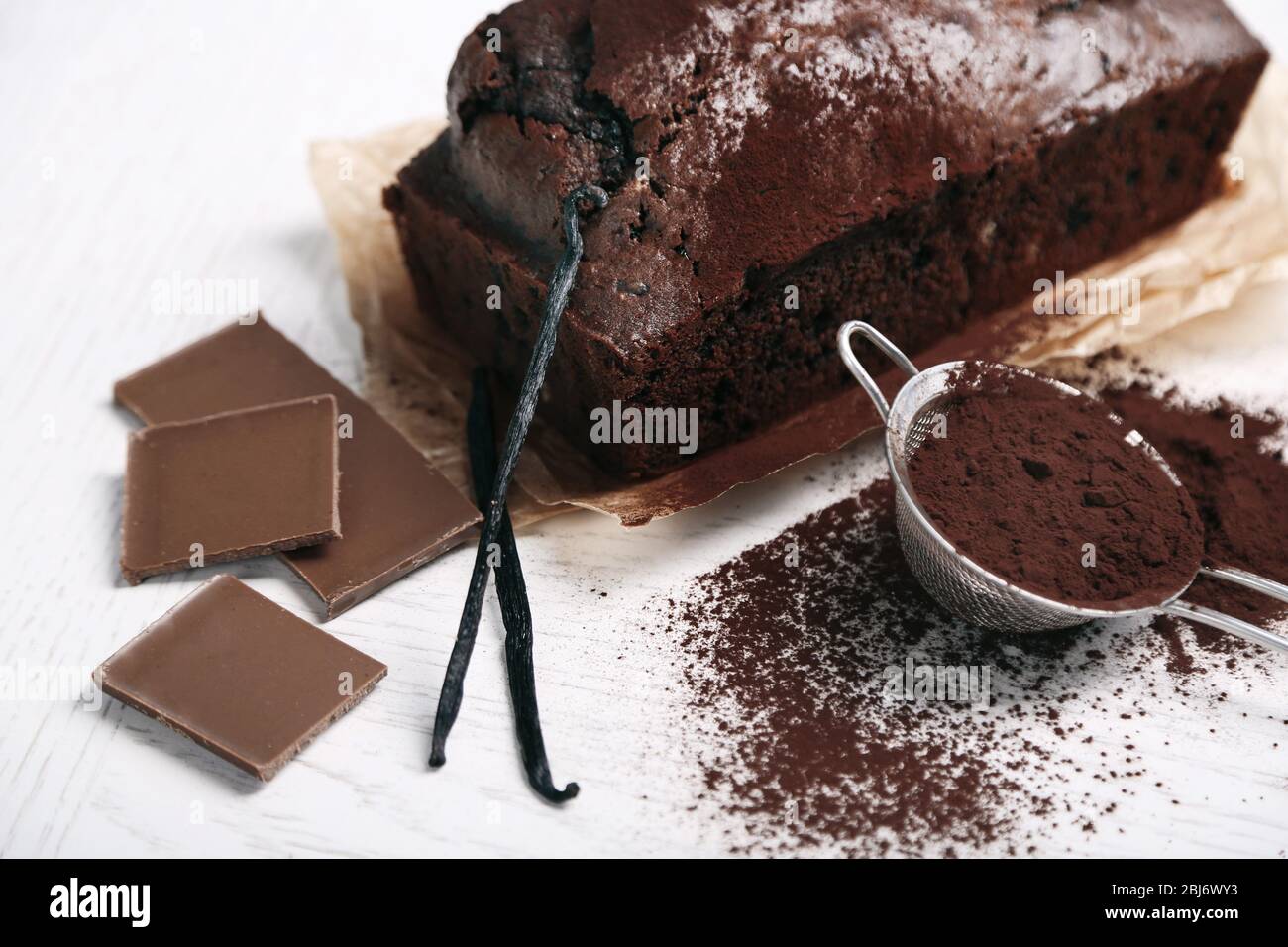 Gâteau au chocolat avec poudre de cacao, gousses de vanille sur table