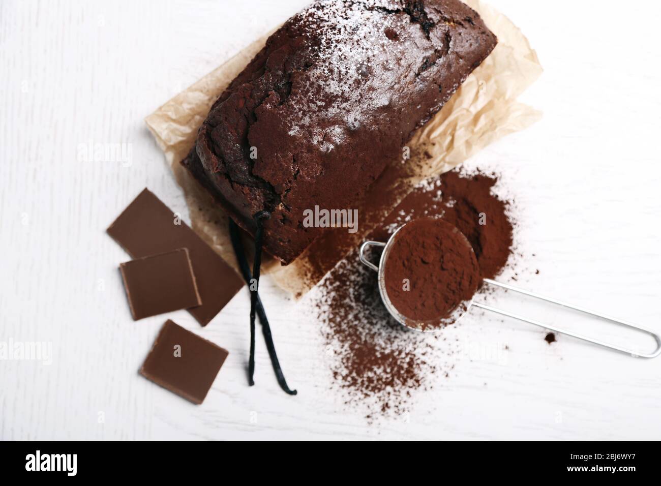 Gâteau au chocolat avec poudre de cacao, gousses de vanille sur table