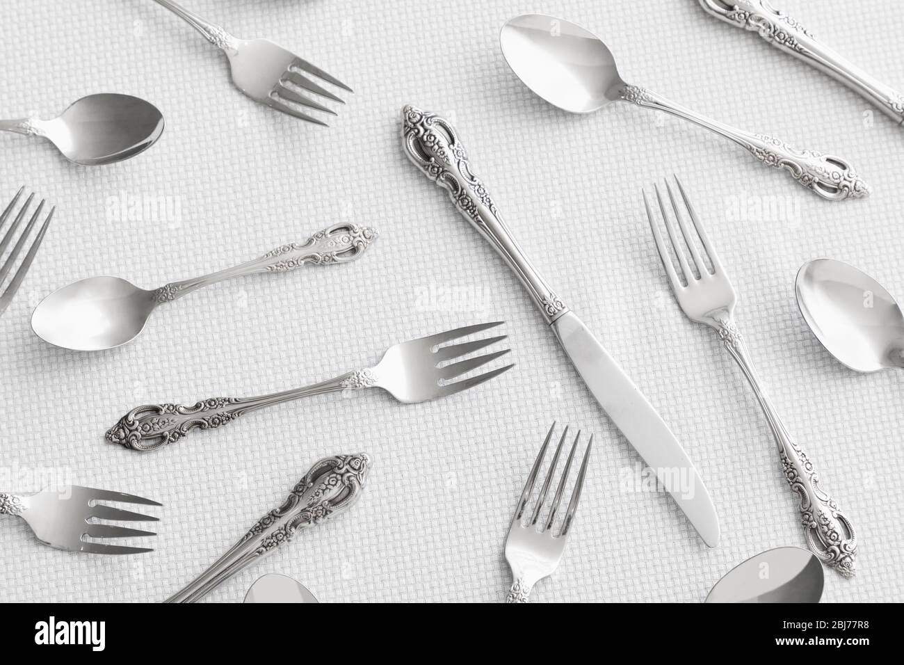 Élégants couverts argentés anciens disposés sur une nappe blanche texturée pour un cadre de repas formel Banque D'Images