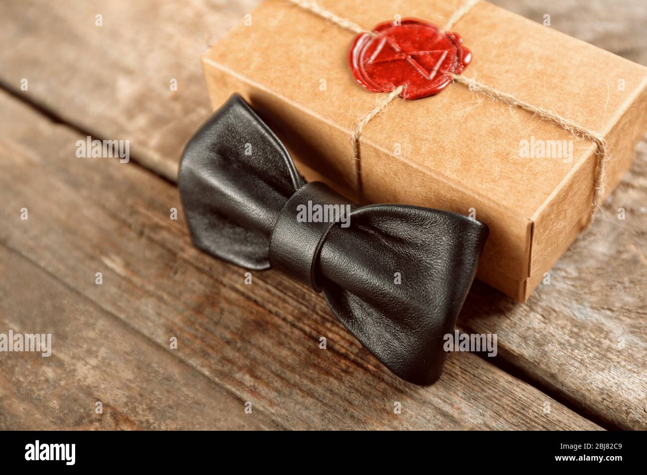 Noeud papillon en cuir noir et boîte cadeau en carton avec joint rouge sur  table en bois, gros plan Photo Stock - Alamy