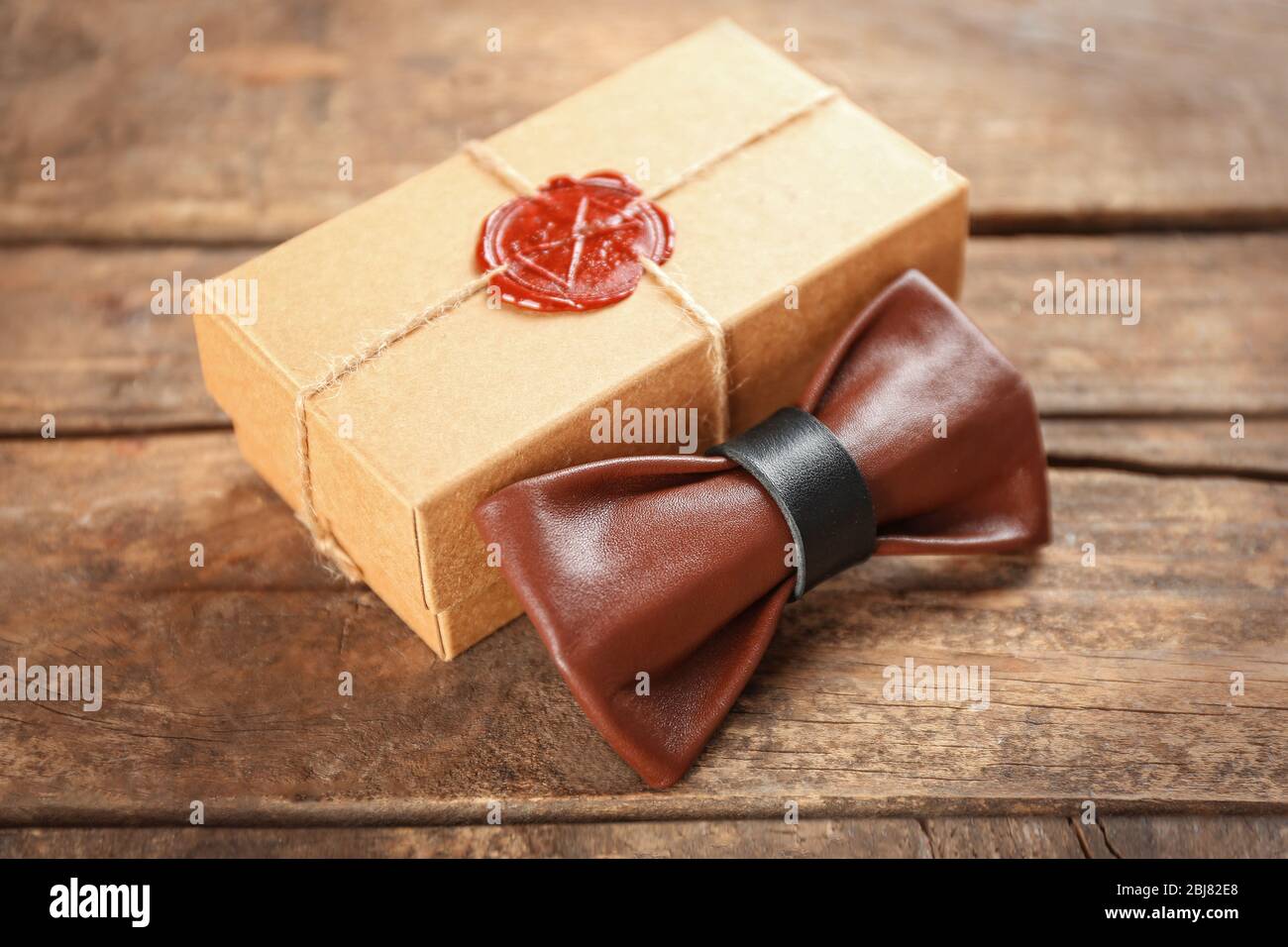 Noeud papillon en cuir marron et noir et boîte cadeau en carton avec joint  rouge sur table en bois, gros plan Photo Stock - Alamy