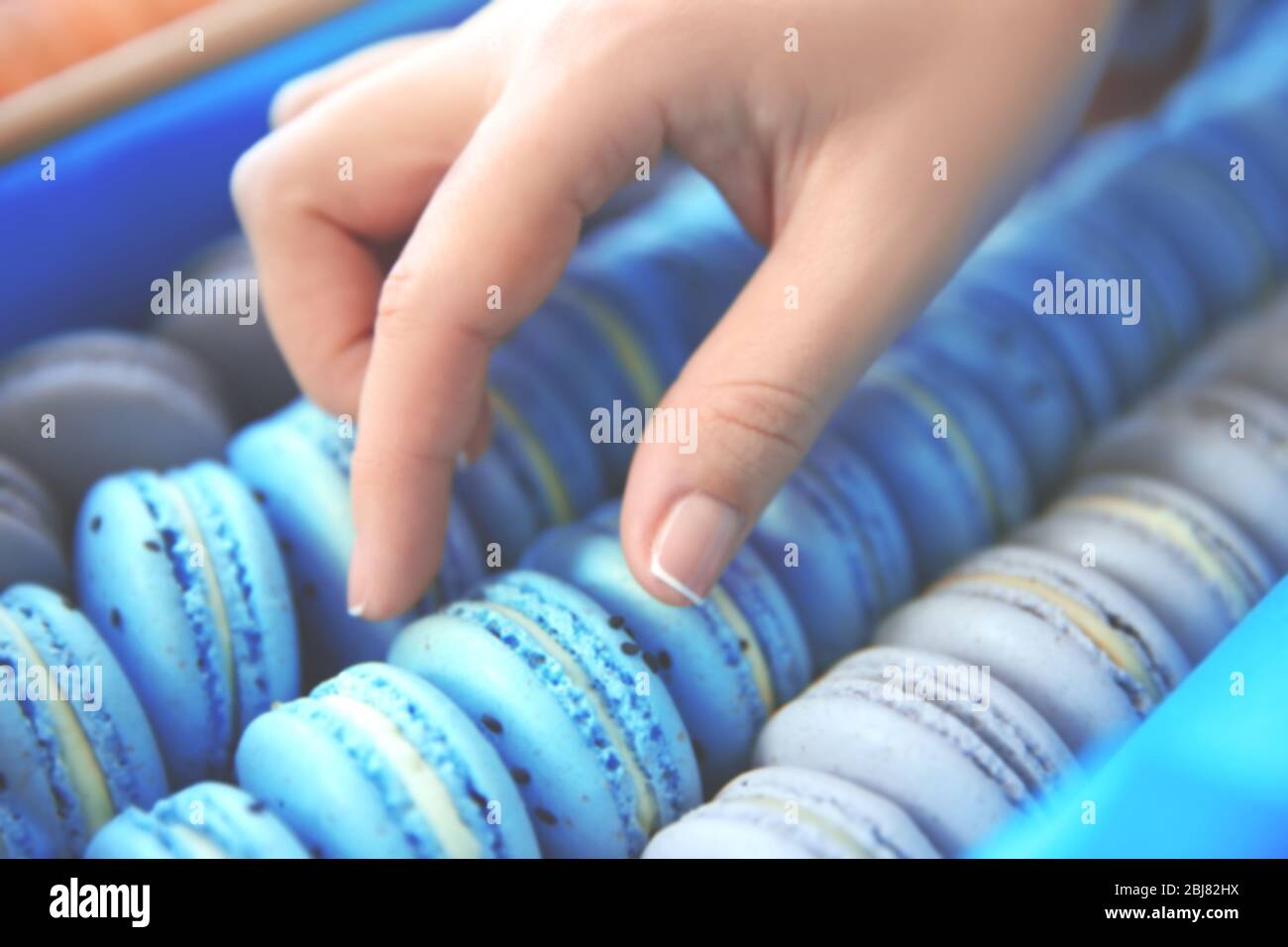 Main féminine prenant de savoureux macarons de la boîte Banque D'Images