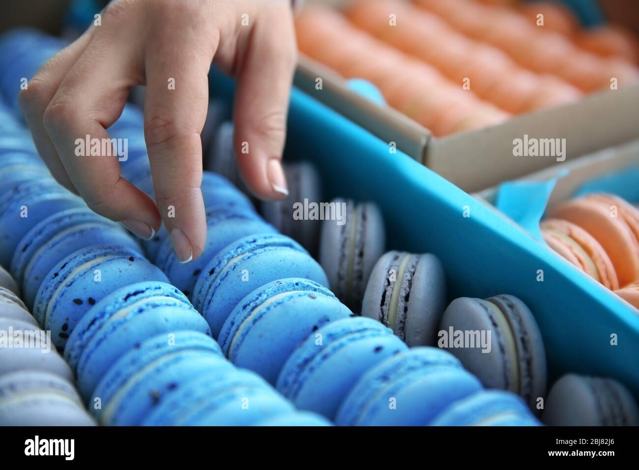 Main féminine prenant de savoureux macarons de la boîte Banque D'Images