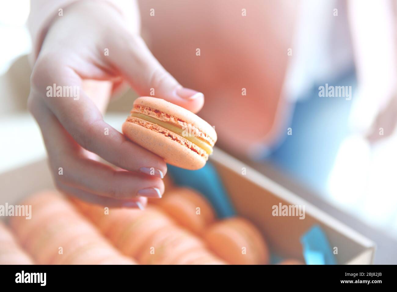 Main féminine prenant de savoureux macarons de la boîte Banque D'Images