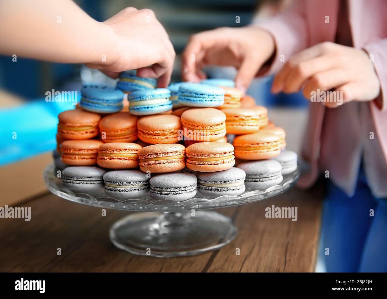 Mains féminines prenant de savoureux macarons de plat sur la table Banque D'Images