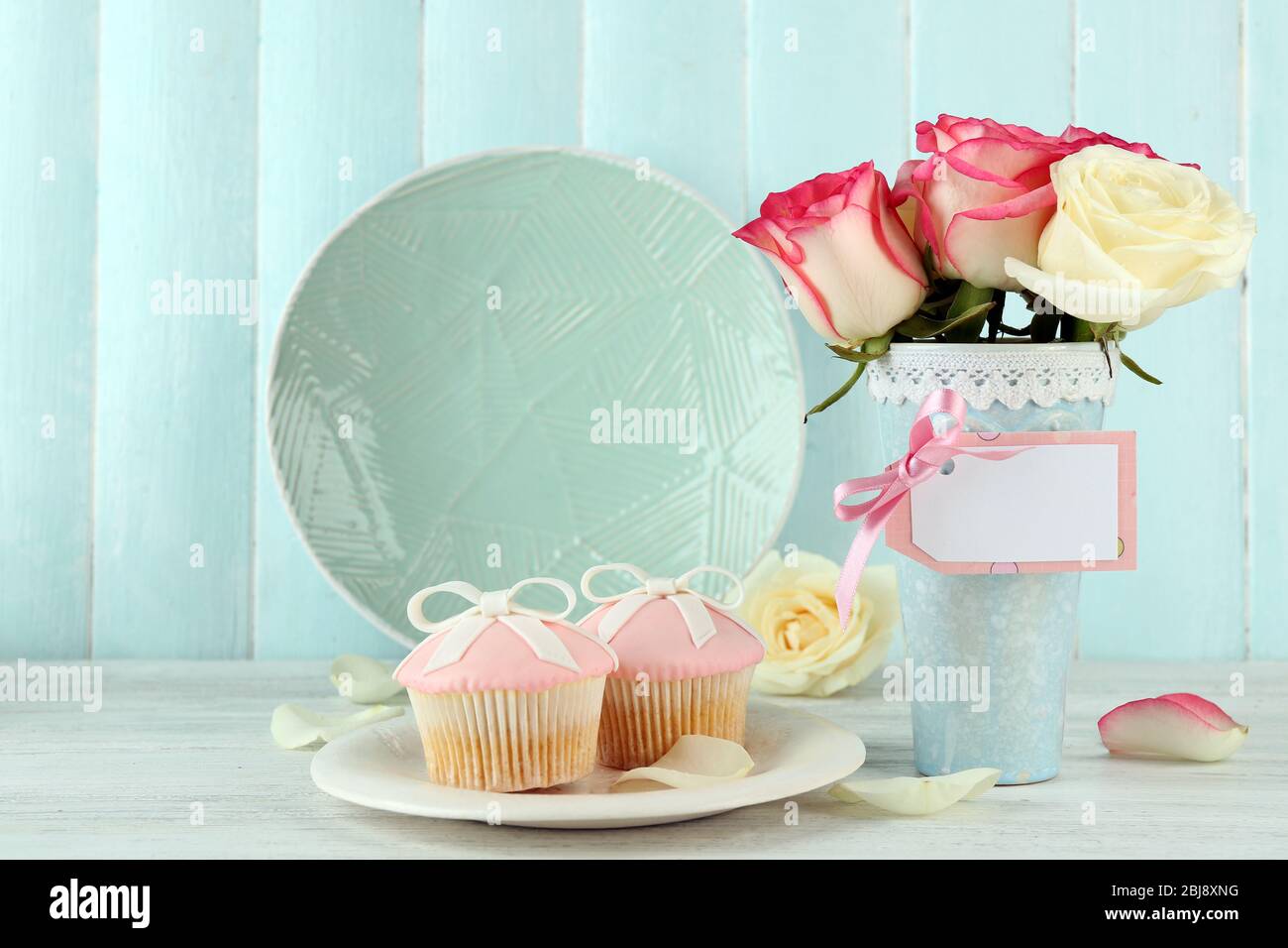 Concept de la fête des mères. Roses dans un vase et cupcakes sur une plaque. Banque D'Images