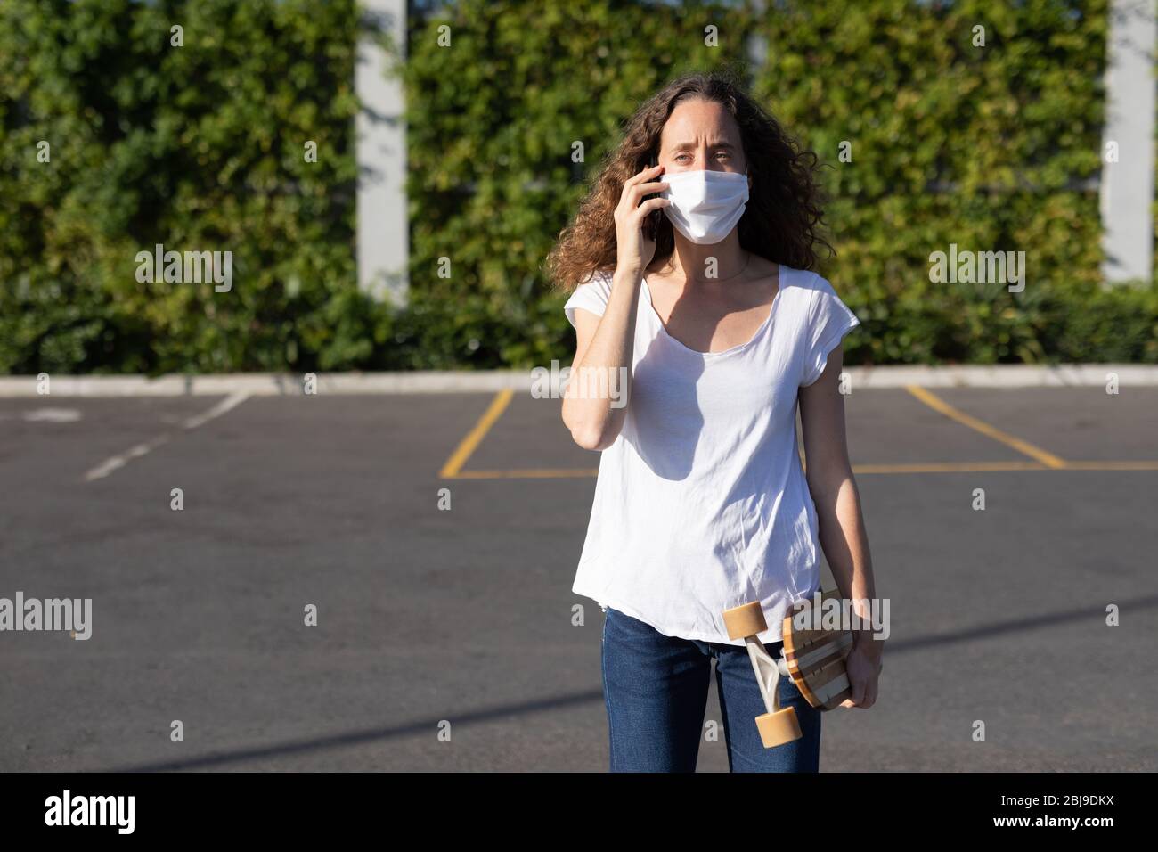 Femme caucasienne portant un masque de protection dans la rue et utilisant son téléphone Banque D'Images