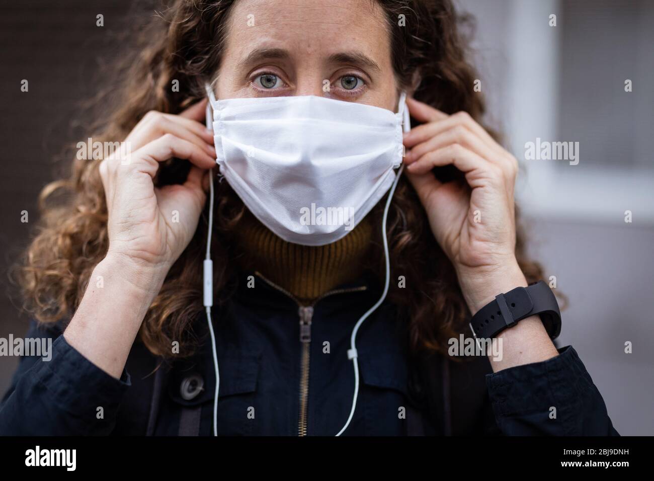 Femme caucasienne mettant un masque de protection dans la rue et regardant la caméra Banque D'Images