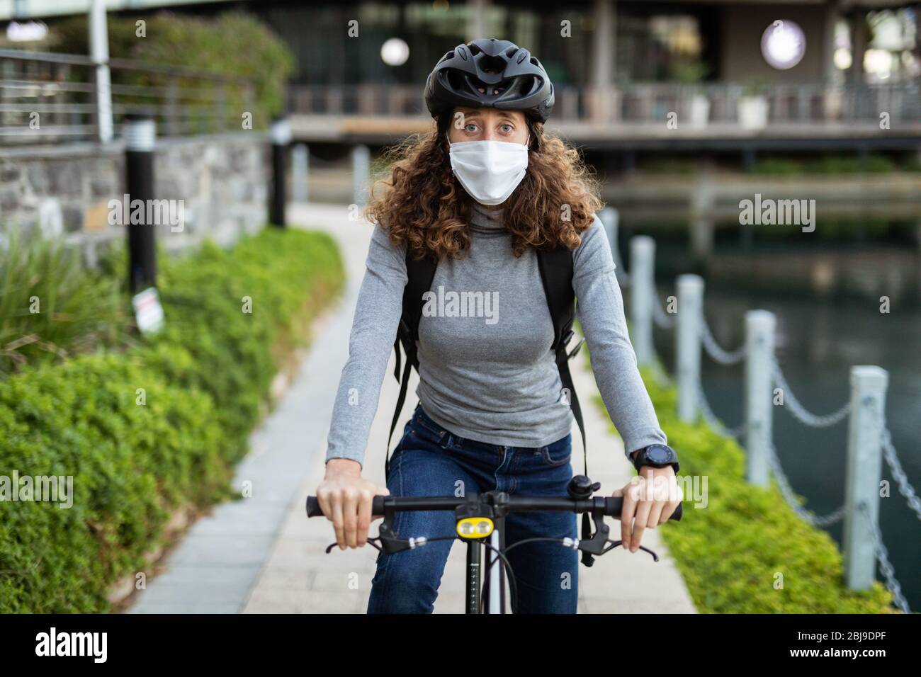 Femme caucasienne portant un masque de protection et un casque de cyclisme  dans la rue, en vélo dans la rue Photo Stock - Alamy