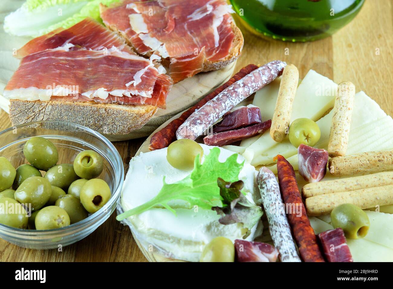 Sandwichs avec jamon, olivesdans un bol en verre. Saucisses Fuet, saucisses chorizo, fromage et bâtonnets de pain sur la plaque en bois. Vitesse méditerranéenne f Banque D'Images