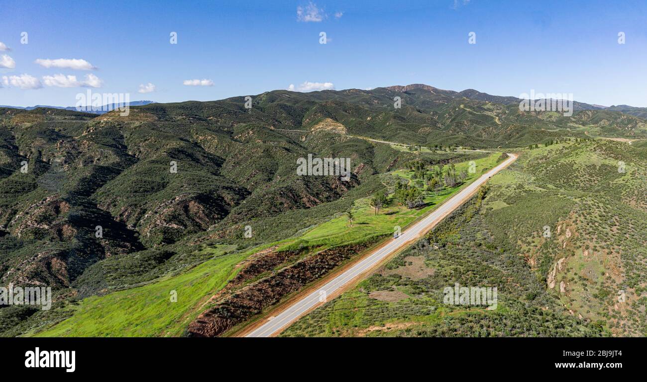 La longue route à deux voies vide mène à travers une vaste nature sauvage boisée verte. Banque D'Images