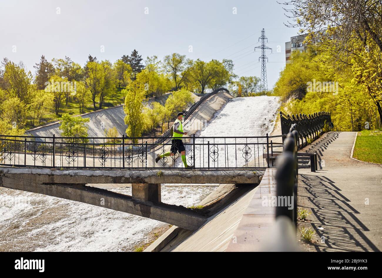 Homme à barbe grise s'exécutant sur le pont de la rivière traversée le matin. Concept de vie sain Banque D'Images