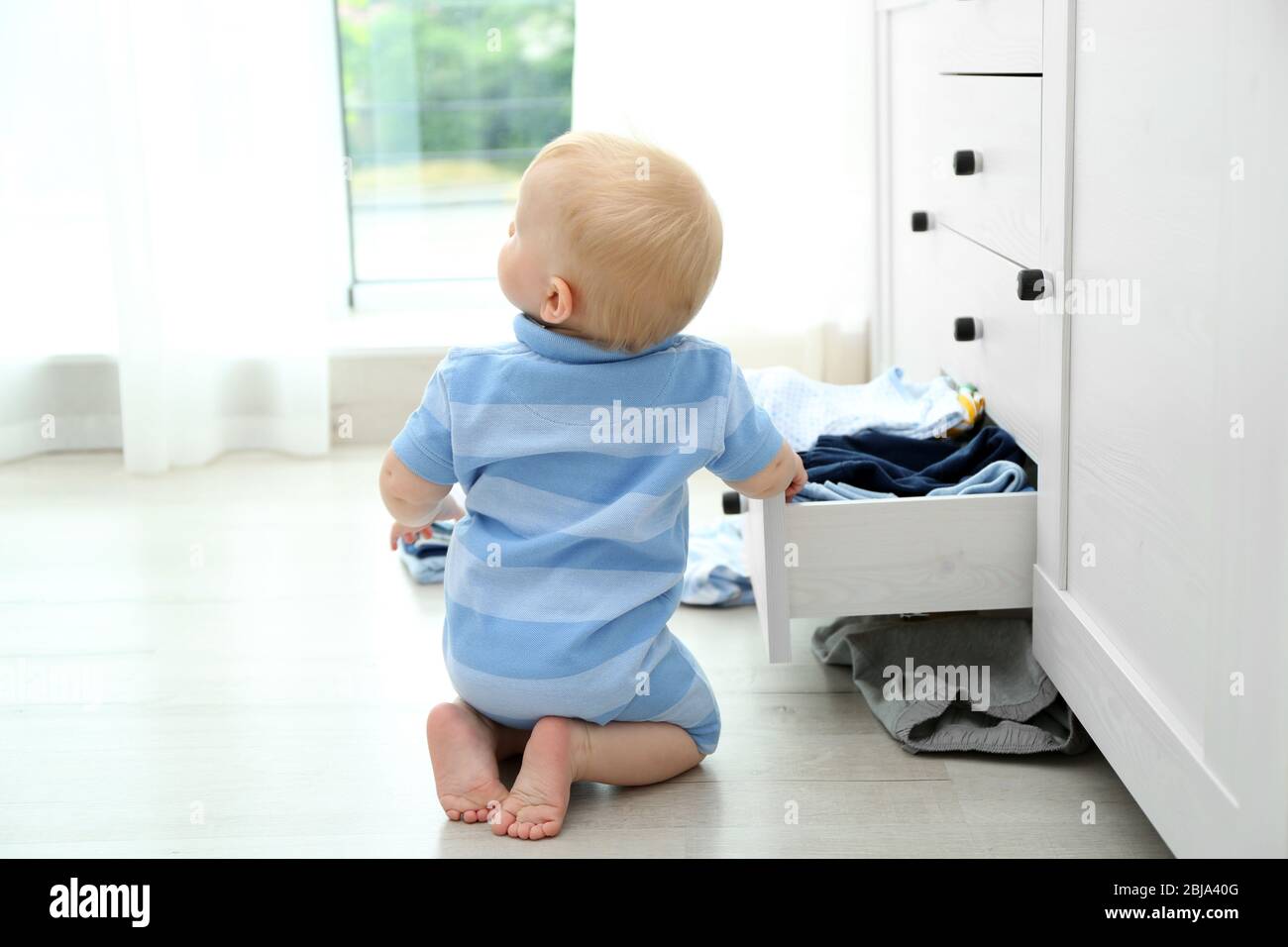 Bébé jetant des vêtements de la poitrine en bois Banque D'Images