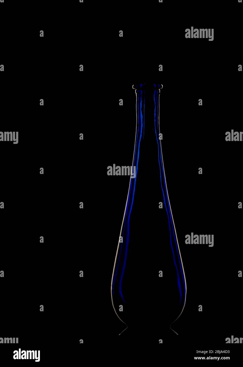 Vase en verre bleu élégant, rétroéclairé, silhouetté sur fond noir. Banque D'Images