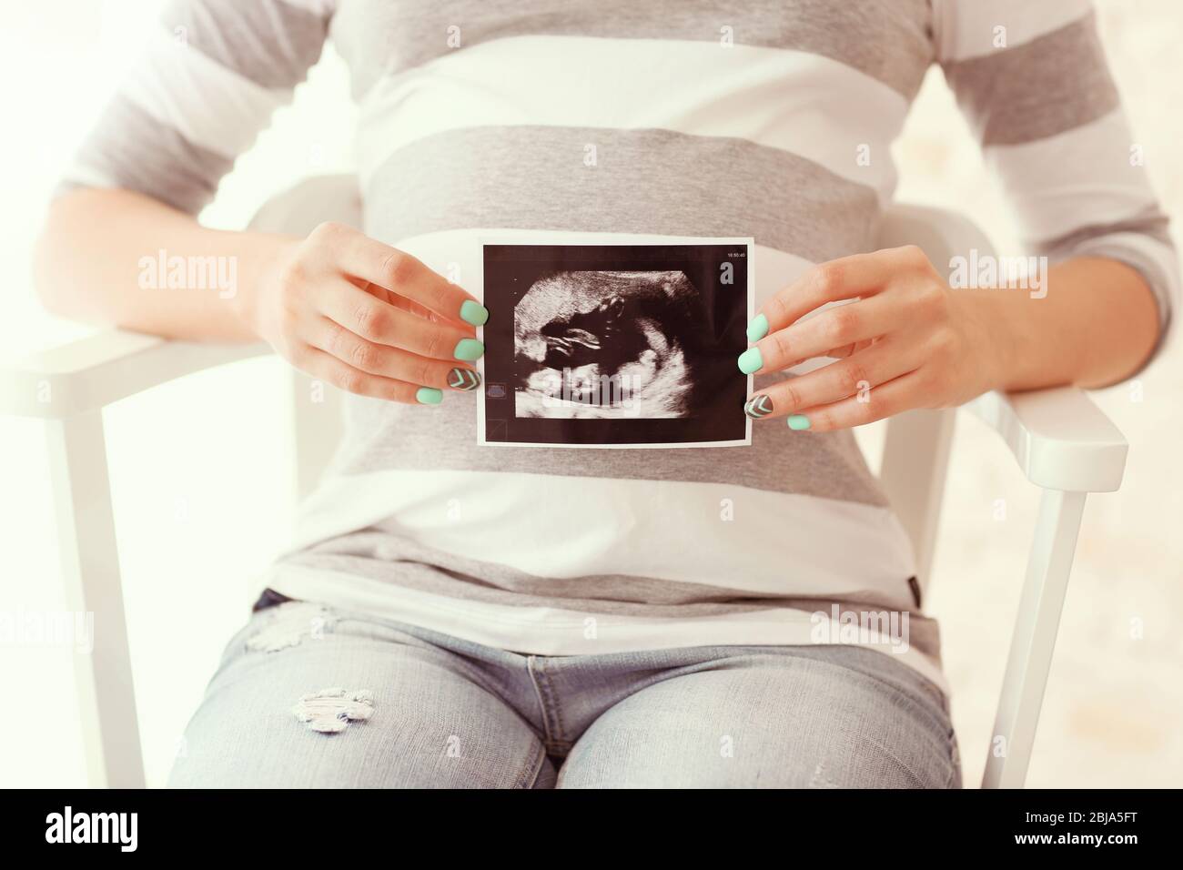 Jeune femme enceinte avec la photo ultra-sonore de son bébé Banque D'Images