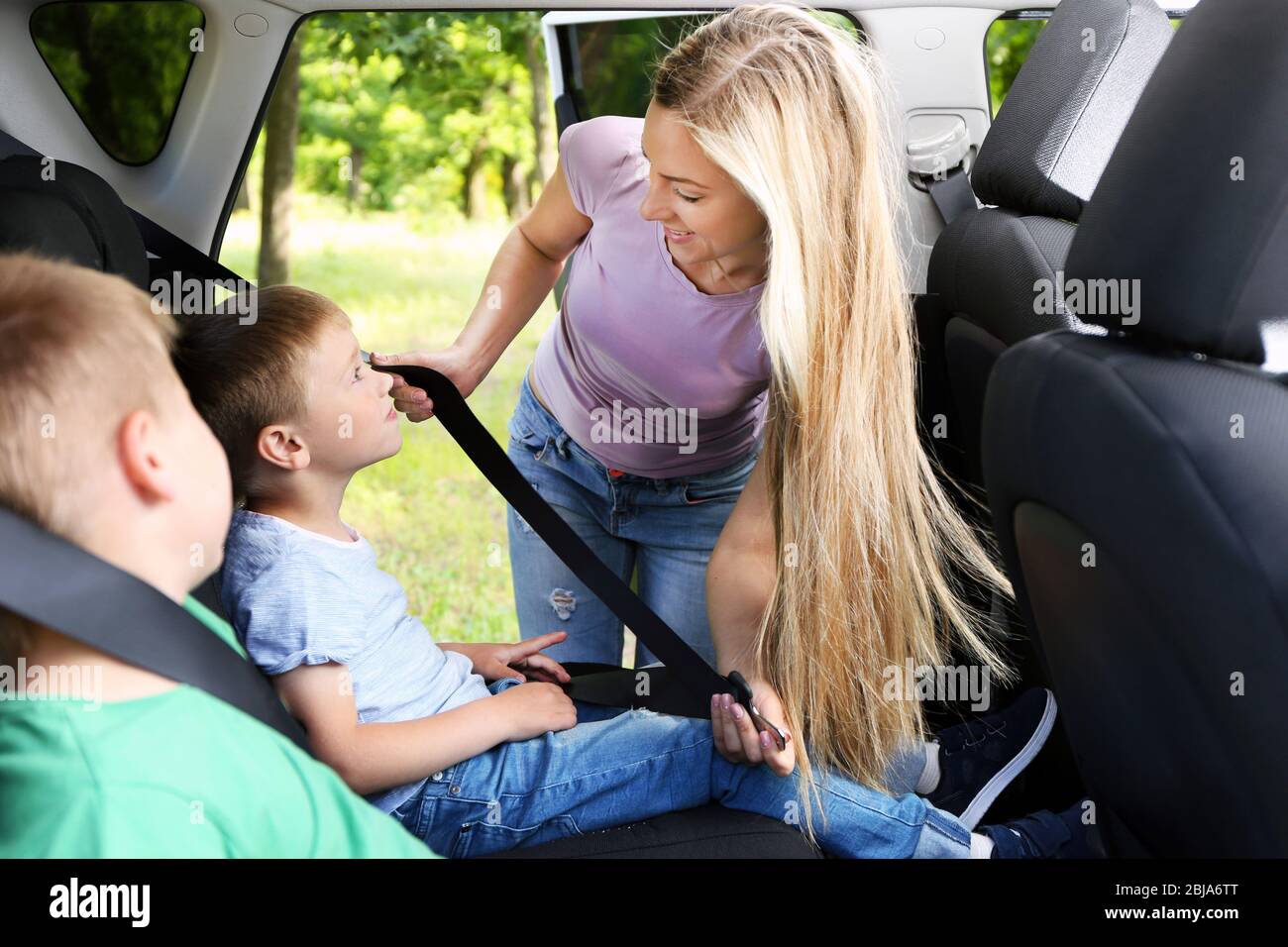 La mère attache la ceinture de sécurité à l'enfant en voiture Photo Stock -  Alamy
