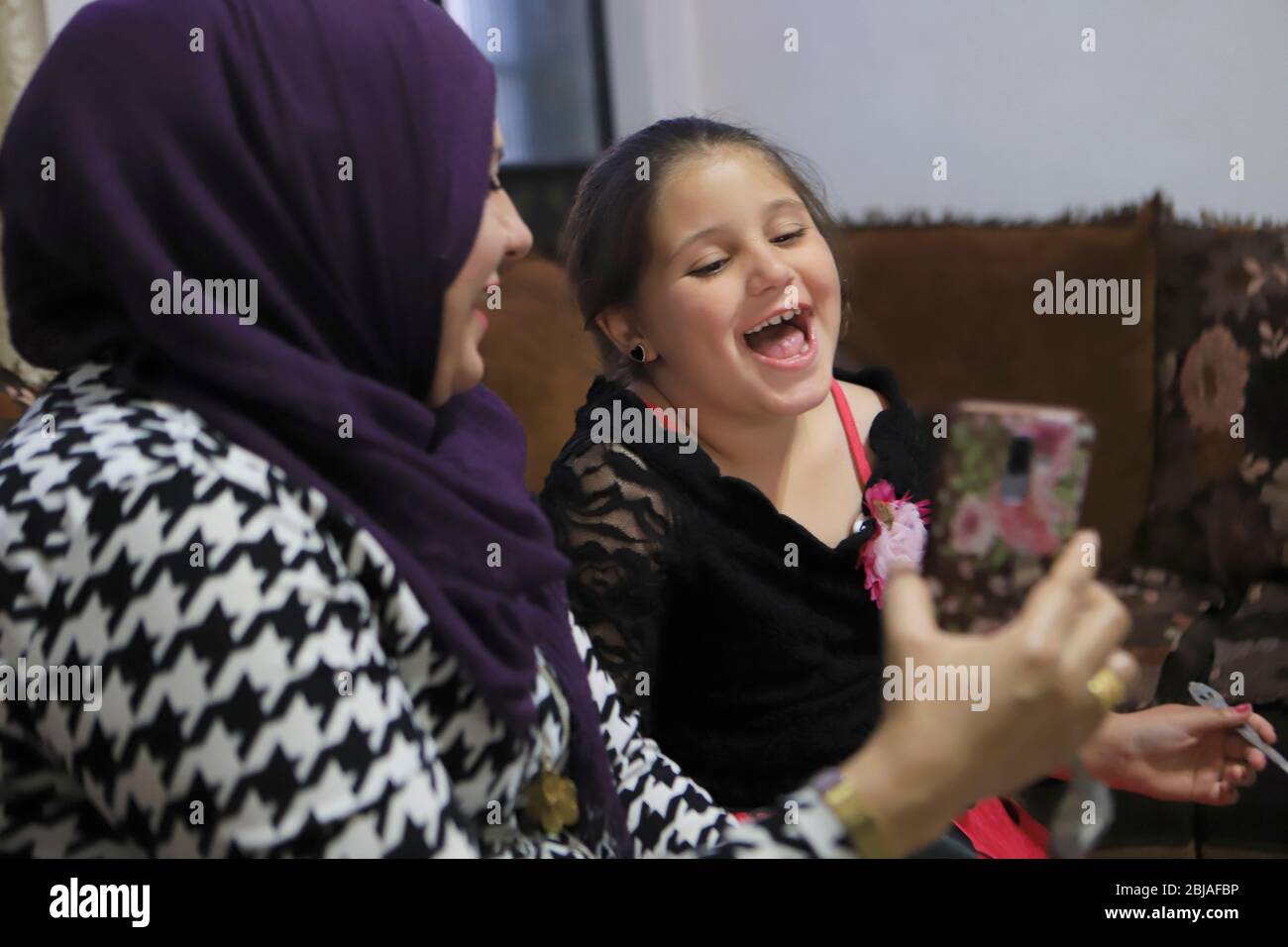 Hébron. 28 avril 2020. La femme palestinienne Reem Abu Ayyah parle à son mari Rami Abu Ayyah via WhatsApp avec sa fille Rama tout en prenant le petit déjeuner dans leur maison de la ville de Hébron, en Cisjordanie, le 28 avril 2020. Rami Abu Ayyah, une infirmière traitant des patients infectés par le COVID-19 à l'hôpital de Ramallah City, ne pouvait pas se réunir avec sa famille pendant le mois Saint du Ramadan. Crédit: Mamoun Wazwaz/Xinhua/Alay Live News Banque D'Images