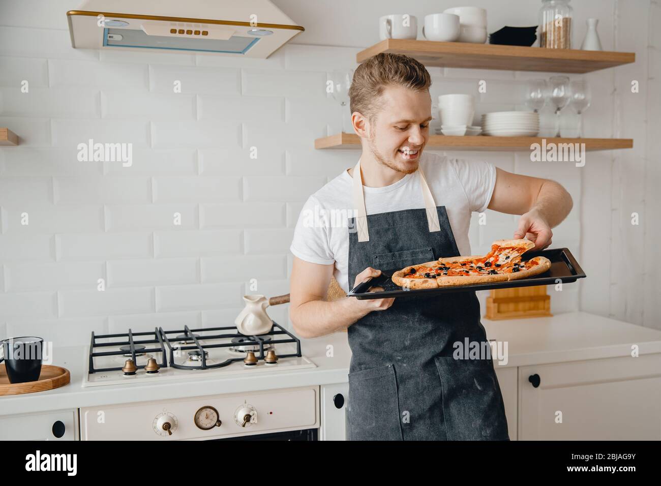 Jeune Homme En Tablier Dans La Cuisine Avec Pizza Maison Prête