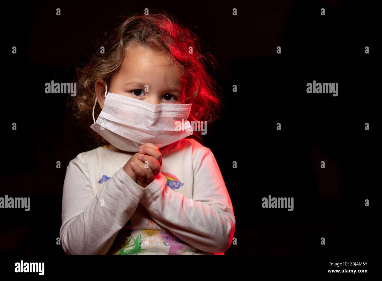 Fille portant un masque de protection contre la pandémie de coronavirus de Covid-19. Elle prie Dieu pour un traitement et de l'aide. Espace de copie. Banque D'Images