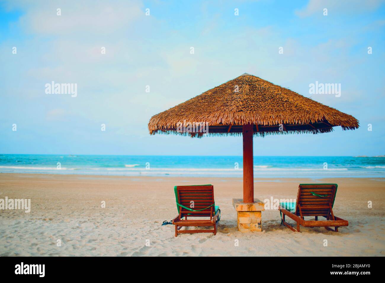 Deux chaises longues et un parasol sur la plage Banque D'Images