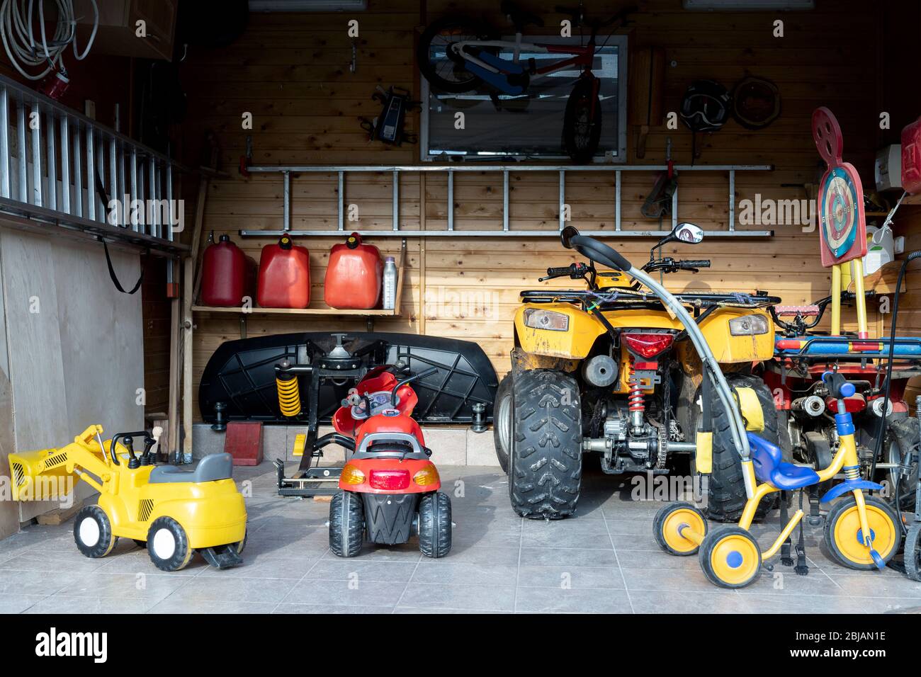 Vue intérieure porte ouverte quad VTT parking de moto garage désordre, des  trucs de désordre, jouets pour enfants et l'intérieur de rangement bicylce  à la maison. Entrepôt de maison Photo Stock -