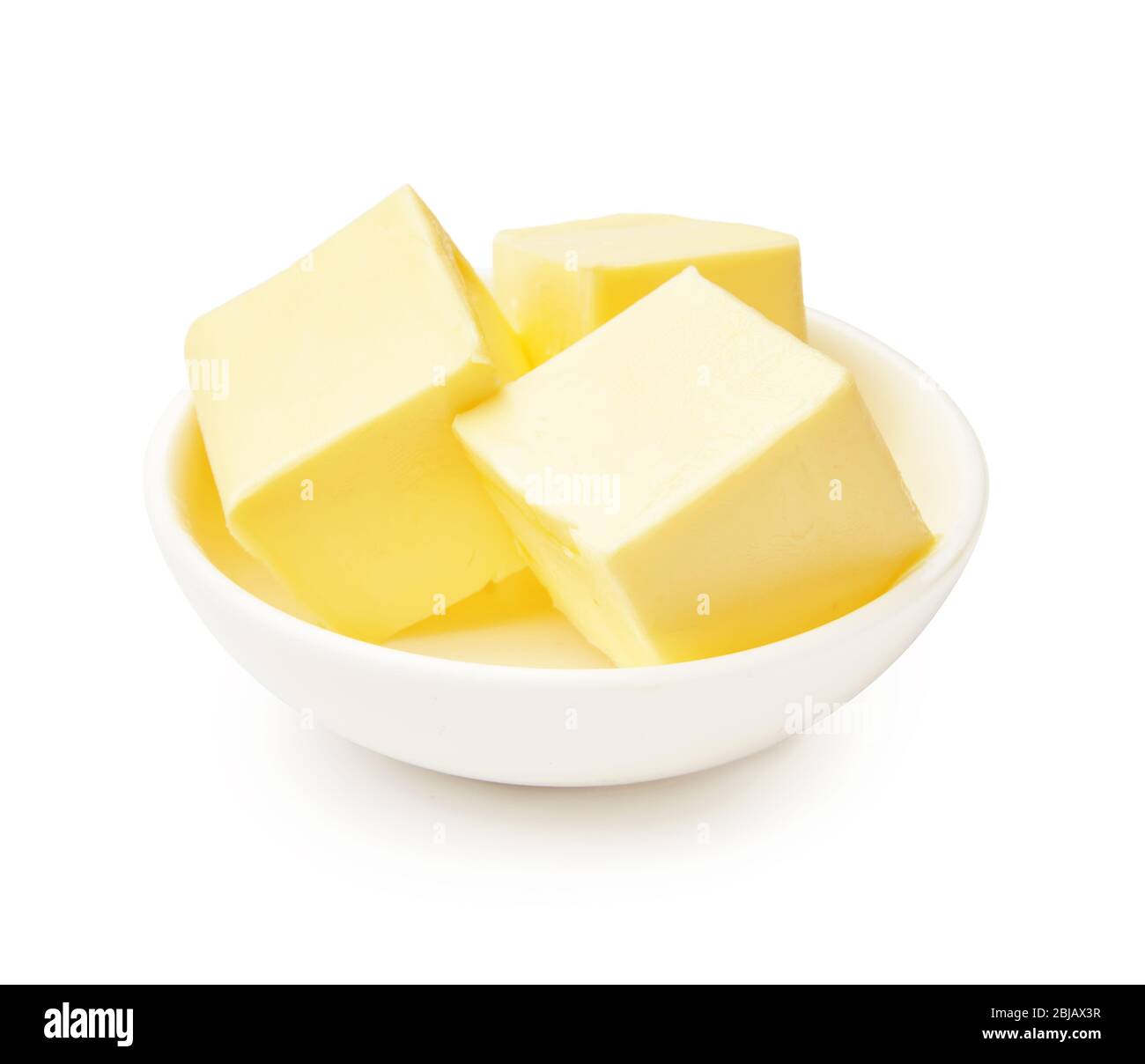 Morceaux de beurre dans un bol blanc isolés sur fond blanc. Cubes de beurre. Banque D'Images