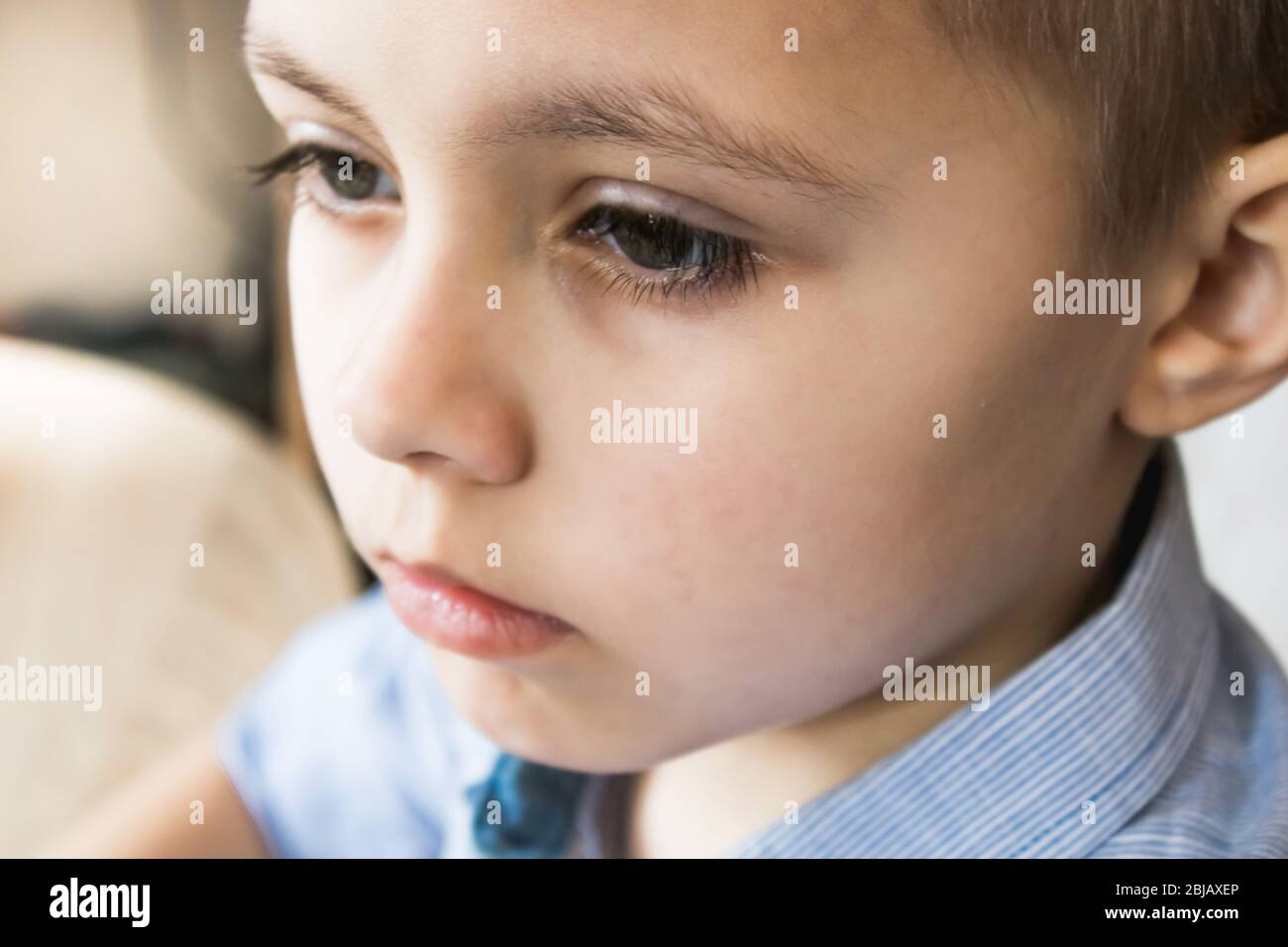 Le visage d'un garçon triste ou réfléchi. Gros plan sur le visage d'un bébé. Banque D'Images