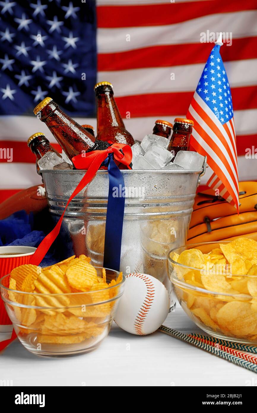 Seau avec bouteilles de bière, chips et boule sur table en bois blanc Banque D'Images