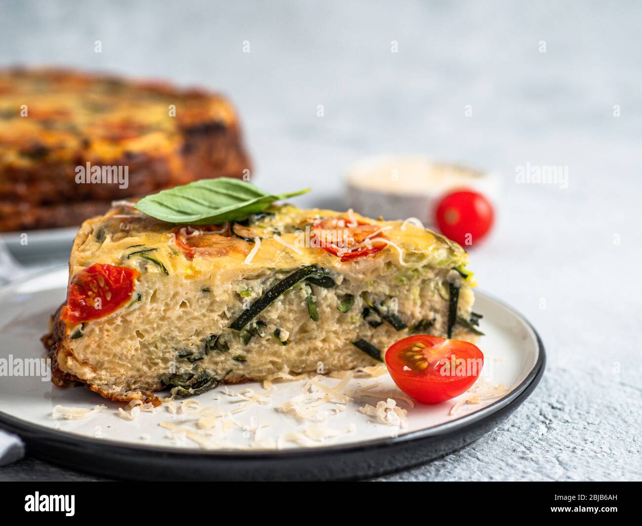 Tarte courgette et ingrédients sur fond gris, l'espace de copie. Morceau de tarte salé délicieux avec les courgettes, les tomates, les herbes et le fromage. Idée et recette pour la cuisson saine et lot à la récolte de courgettes Banque D'Images