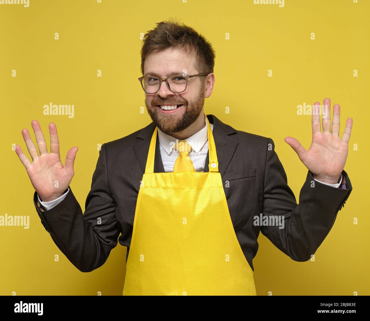 Étrange, charmant homme d'affaires dans un costume noir et tablier jaune, fait beaucoup, il se réjouit, sourires et soulève des palmiers. Banque D'Images