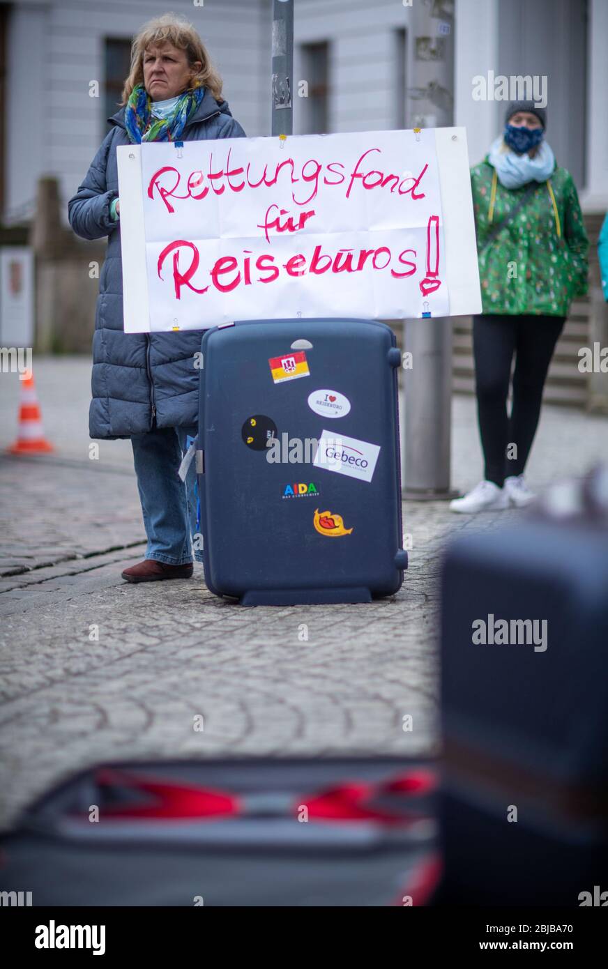 Schwerin, Allemagne. 29 avril 2020. Avec une valise et un panneau disant « Fonds de secours pour les agences de voyage », une femme se tient devant la chancellerie d'État lors d'une action de protestation. Compte tenu des faibles taux d'infection dans la région de Mecklembourg-Poméranie occidentale, les experts du voyage réclament une normalisation dans la crise de Corona. Jusqu'à 50 représentants des voyagistes utilisent l'action pour attirer l'attention sur leur situation économique difficile. D'autres participants ne sont pas autorisés en raison des règles de distance Corona actuelles. Crédit: Jens Büttner/dpa-Zentralbild/dpa/Alay Live News Banque D'Images