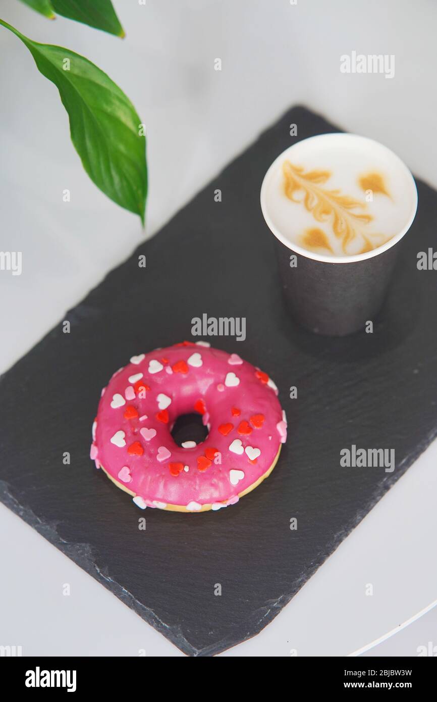 Plateau avec un beignet et du café sur la table. Banque D'Images