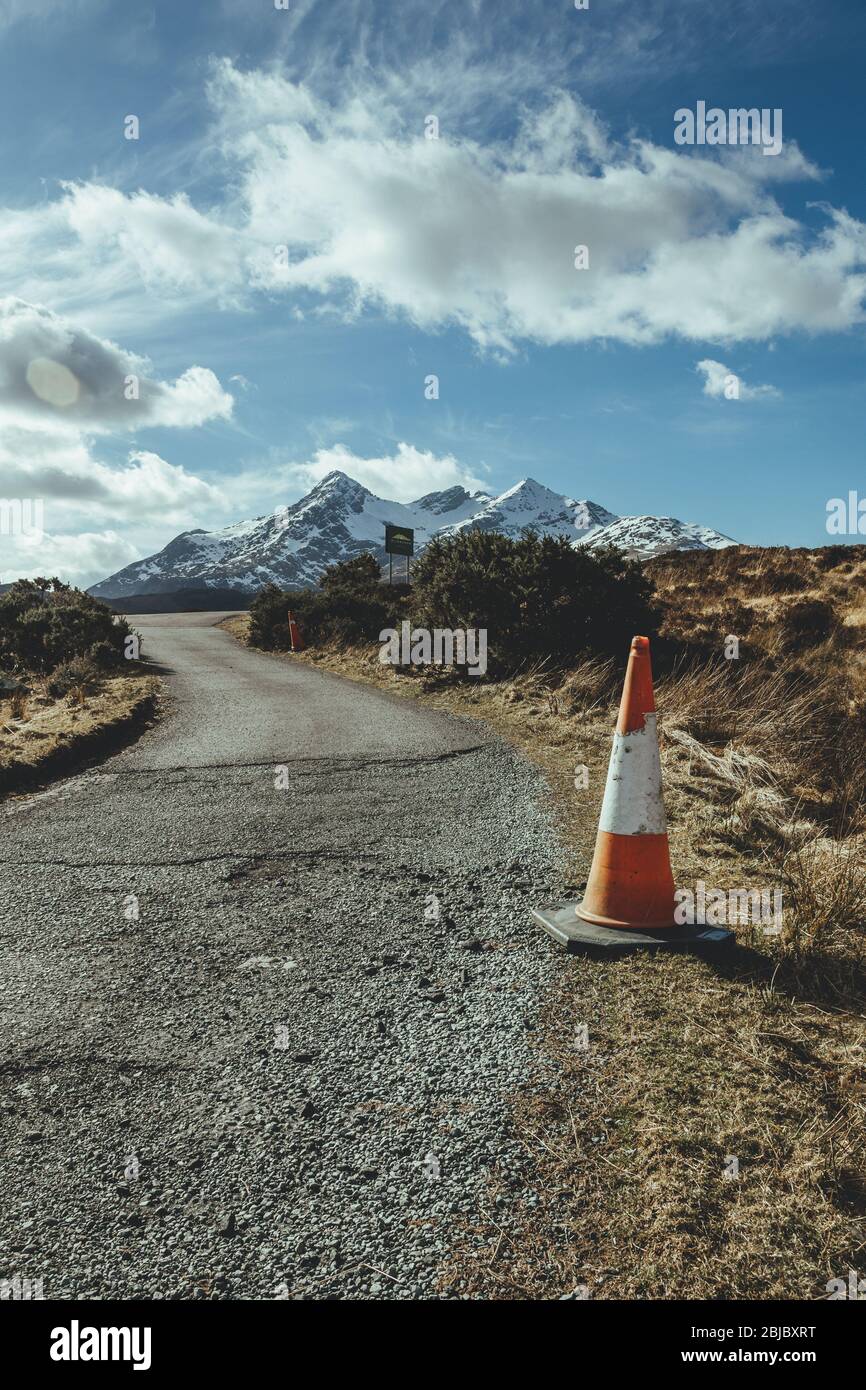 Cône de sécurité sur un côté de la route en terrain accidenté avec des montagnes enneigées sur le fond près de Sligachan sur l'île de Skye au nord de SCO Banque D'Images