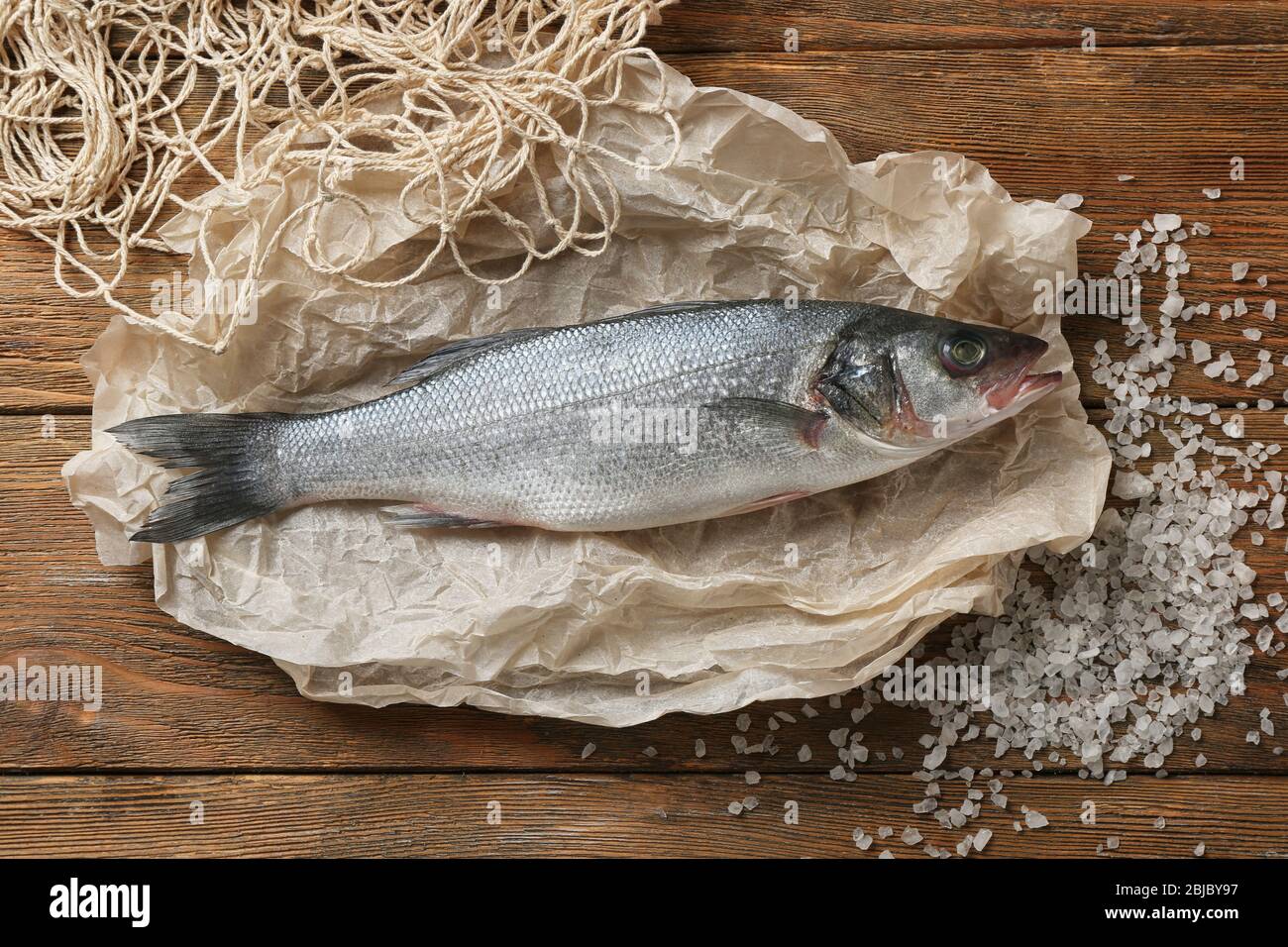 Poisson cru avec filet et sel sur table en bois Banque D'Images
