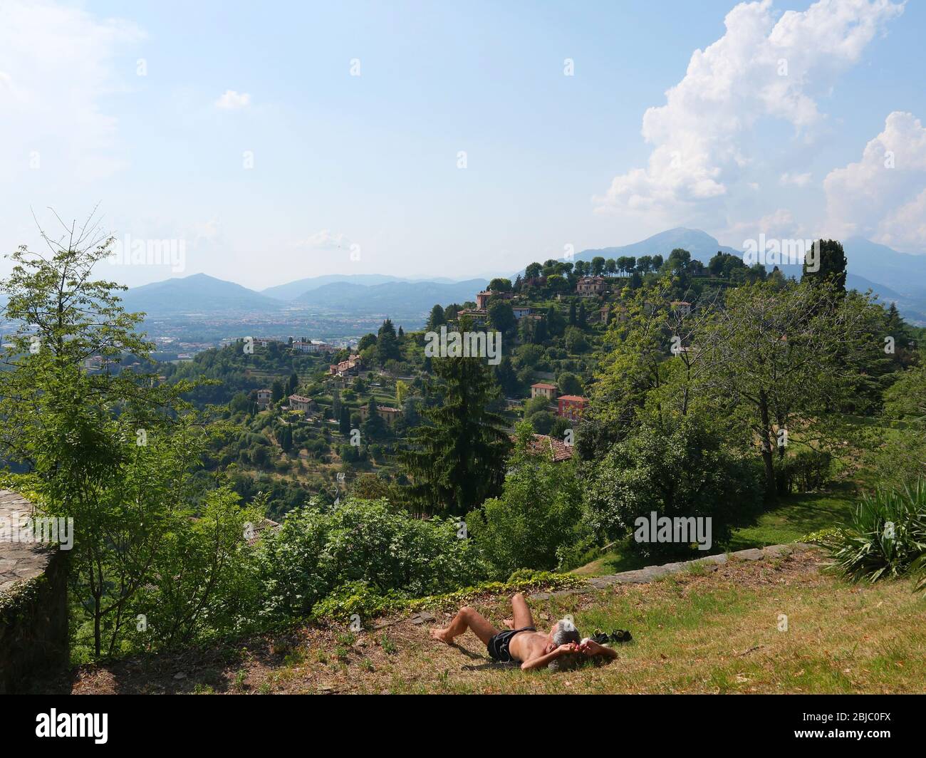 Un homme qui a un bain de soleil avec une vue magnifique sur la petite ville dans une vallée verte luxuriante Banque D'Images