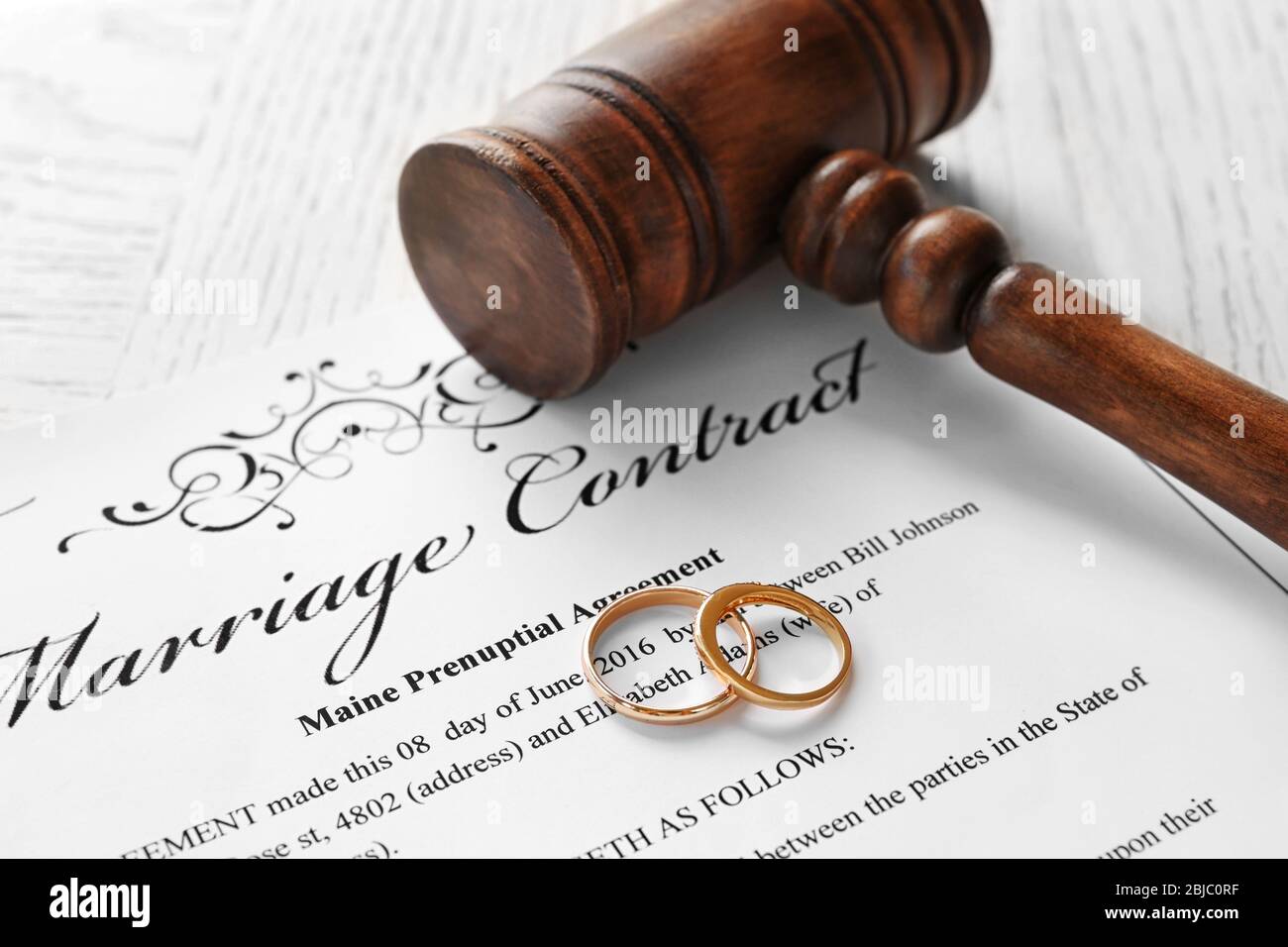 Anneaux de mariage d'or avec le juge gavel sur le contrat de mariage, clôture Banque D'Images