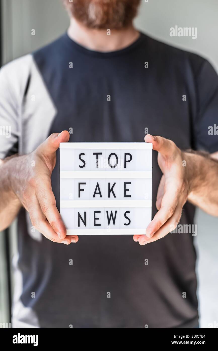 Fausses nouvelles infodemics pendant le concept de pandémie de Covid-19. Mains de l'homme tenant la visionneuse avec du texte Arrêter fausses nouvelles au premier plan. Les gens veulent connaître la tendance Banque D'Images