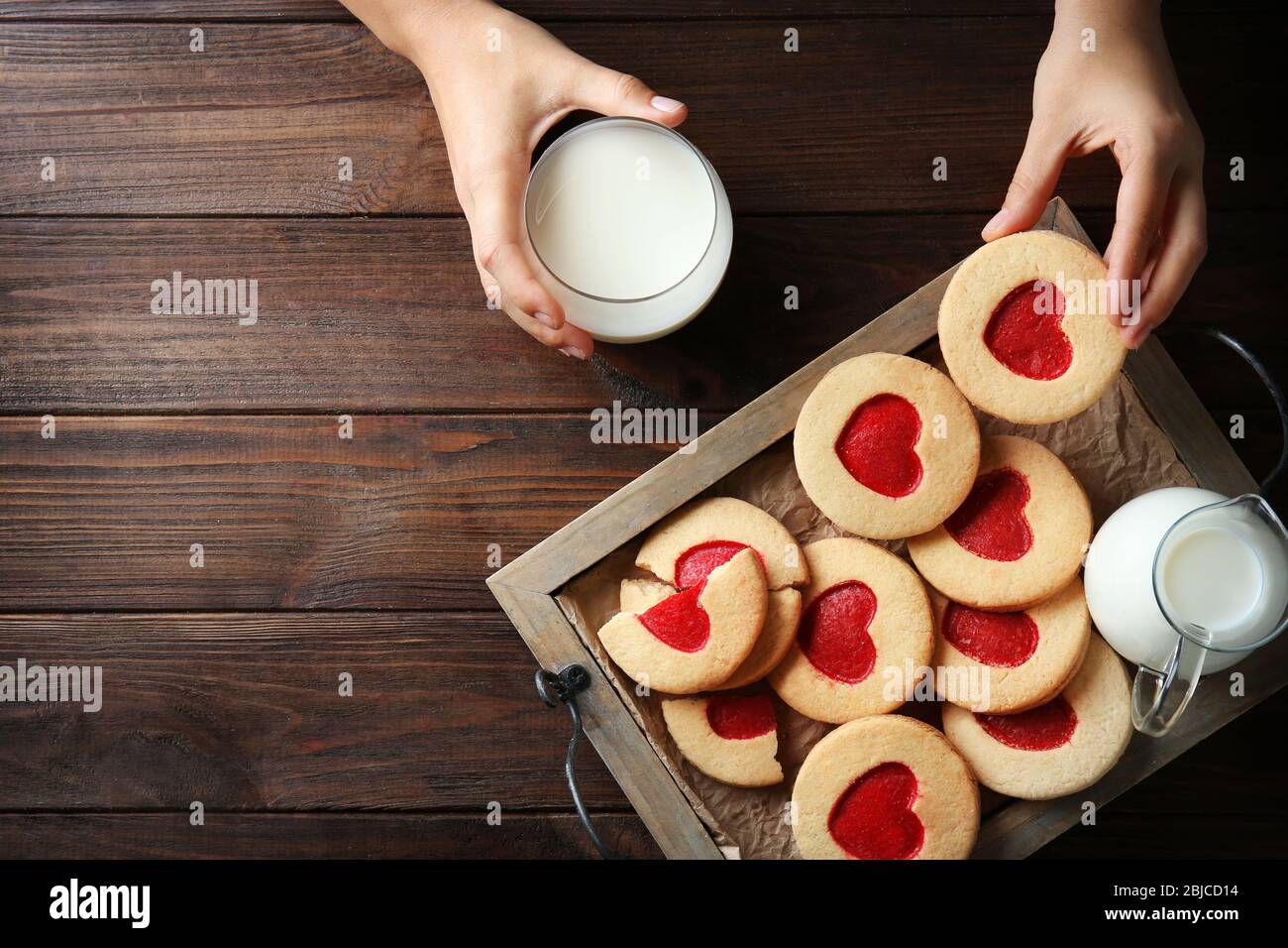 Mains féminines avec lait et biscuits sur table en bois, vue de dessus Banque D'Images