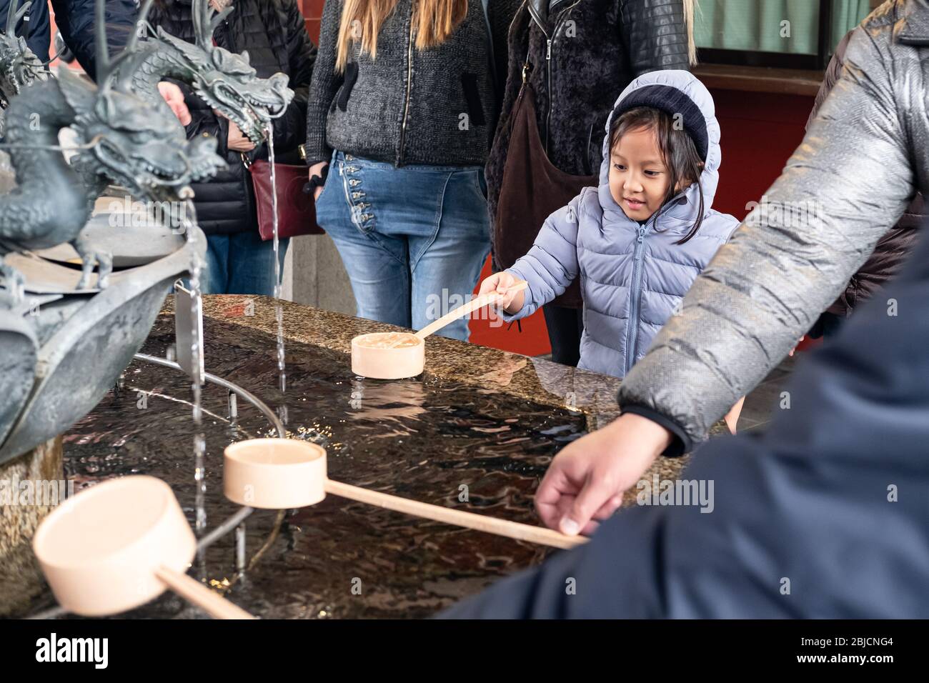Japon, Tokyo Hot Spot, Kid raboutant l'eau par balancier en bois à temizuya, chozuya avant d'entrer dans le sanctuaire au Temple Sensoji, Temple Asakusa Kannon Banque D'Images