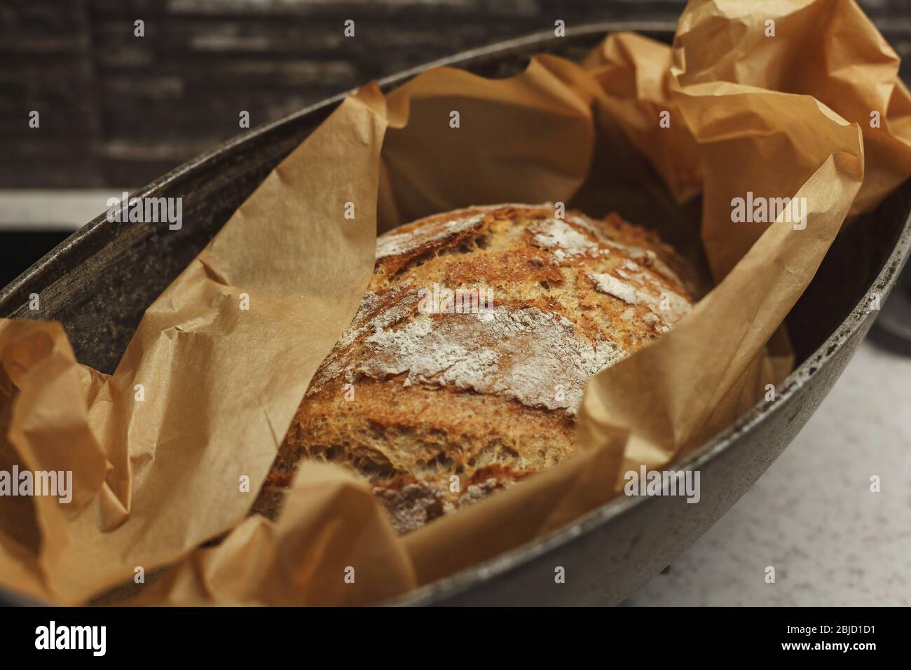 Pain fraîchement cuit de pain maison enveloppé dans du papier à pâtisserie  à l'intérieur d'une plaque de cuisson en acier Photo Stock - Alamy