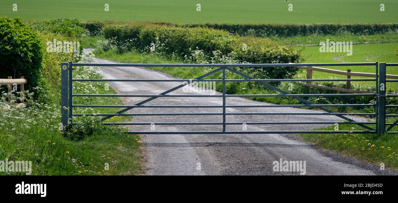Portail sur la route agricole qui refuse l'accès aux véhicules mais qui permet toujours aux marcheurs de passer par un sentier. Banque D'Images