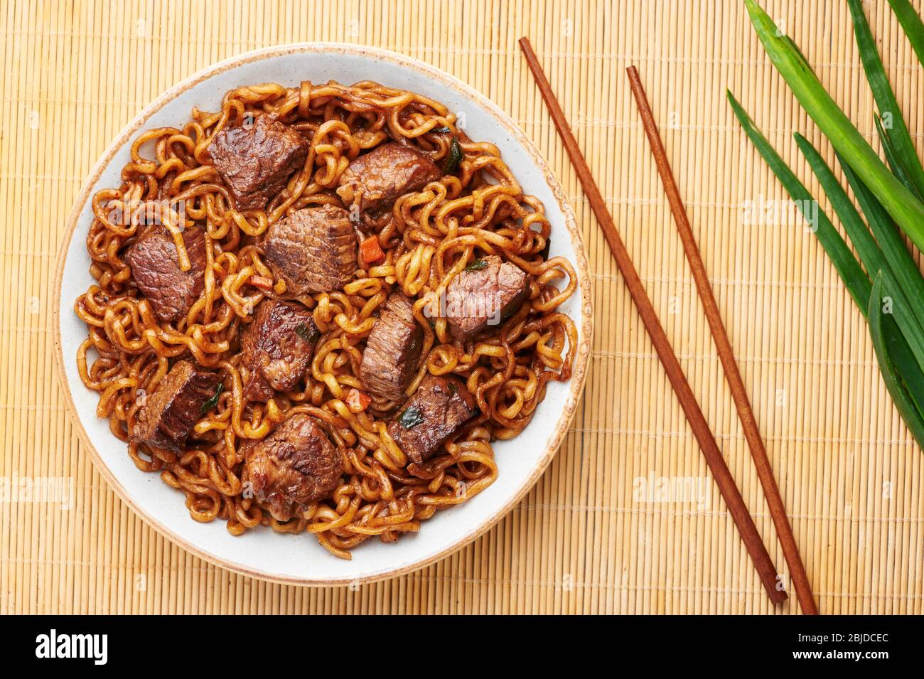 Nouilles RAM-Don ou Chapaguri avec steak de boeuf dans un bol blanc. Jjapaguri est un plat populaire sud-coréen avec des ramen et des nouilles udon et des steaks de boeuf. Copier Banque D'Images