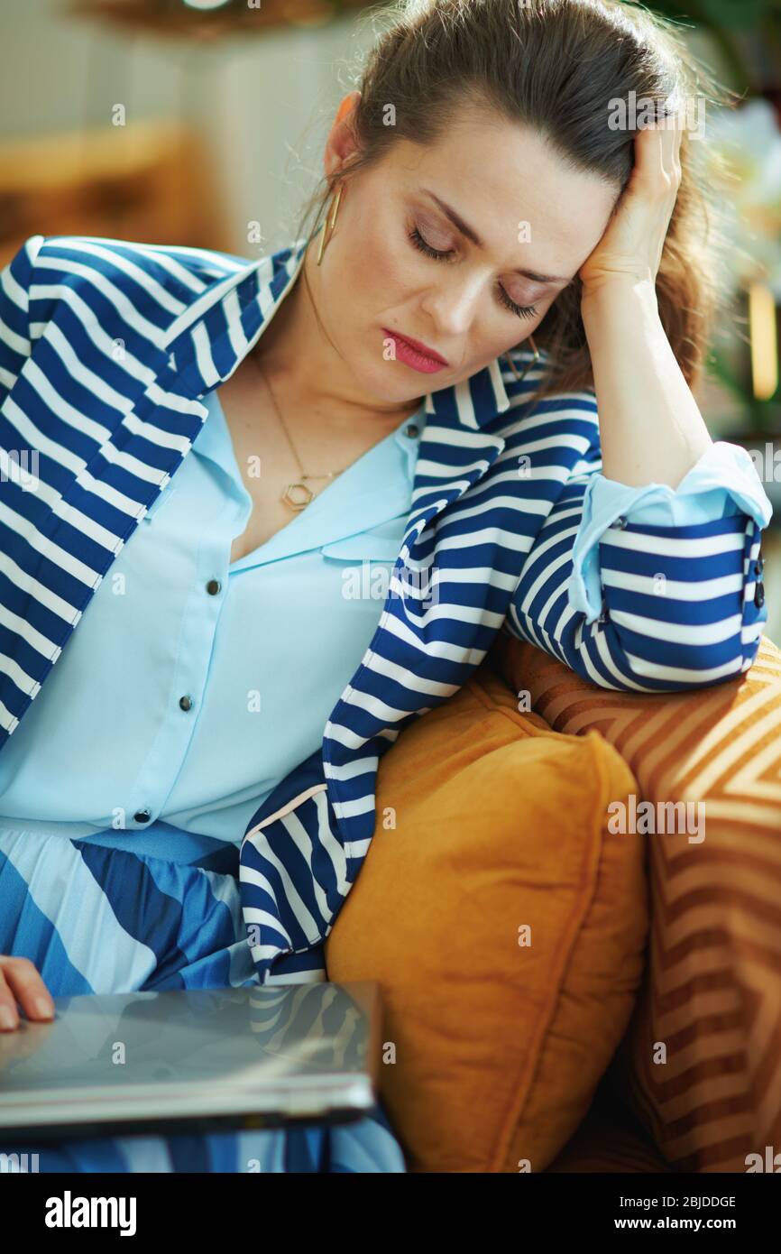femme moderne stressée avec chemisier bleu et veste rayée dorment devant un  ordinateur portable assis sur un divan avec ordinateur portable dans le  salon moderne en plein soleil Photo Stock - Alamy