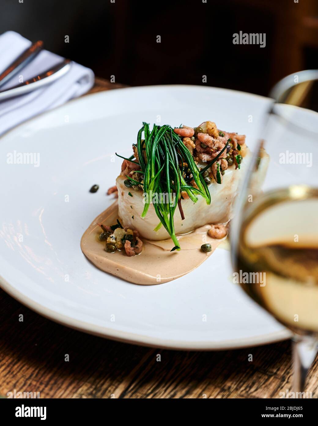 Filet de morue cornouée aux crevettes brunes et pâte de chou-fleur, servi dans une assiette blanche dans un restaurant étoilé au michelin à Londres Banque D'Images