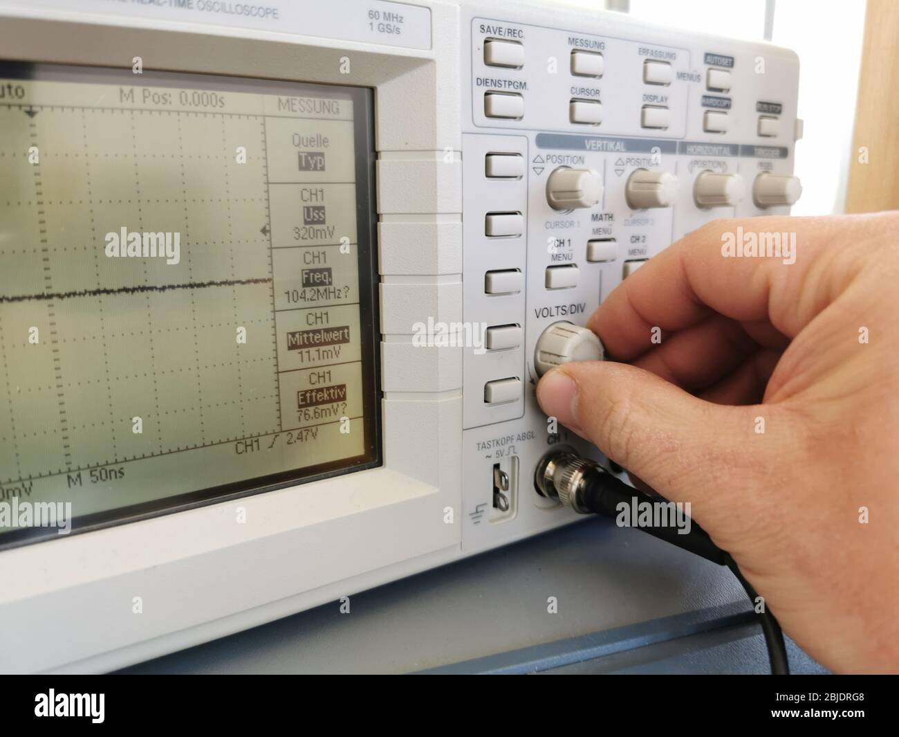 Le technicien en électronique règle un oscilloscope pour mesurer une fréquence Banque D'Images