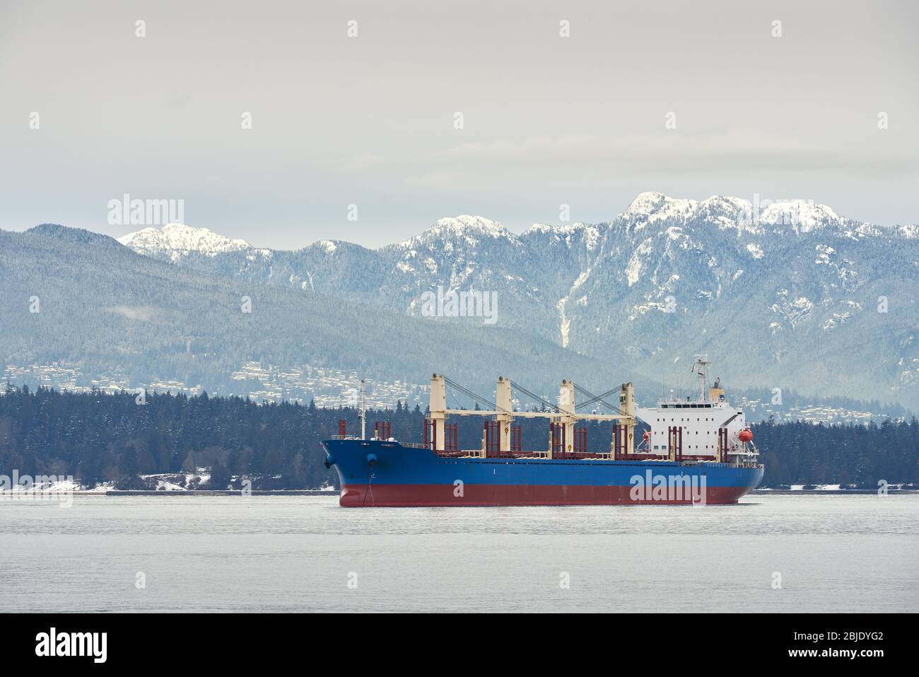 English Bay Freighter Vancouver Snow. Les montagnes côtières enneigées derrière un cargo de la baie English, Vancouver. Banque D'Images