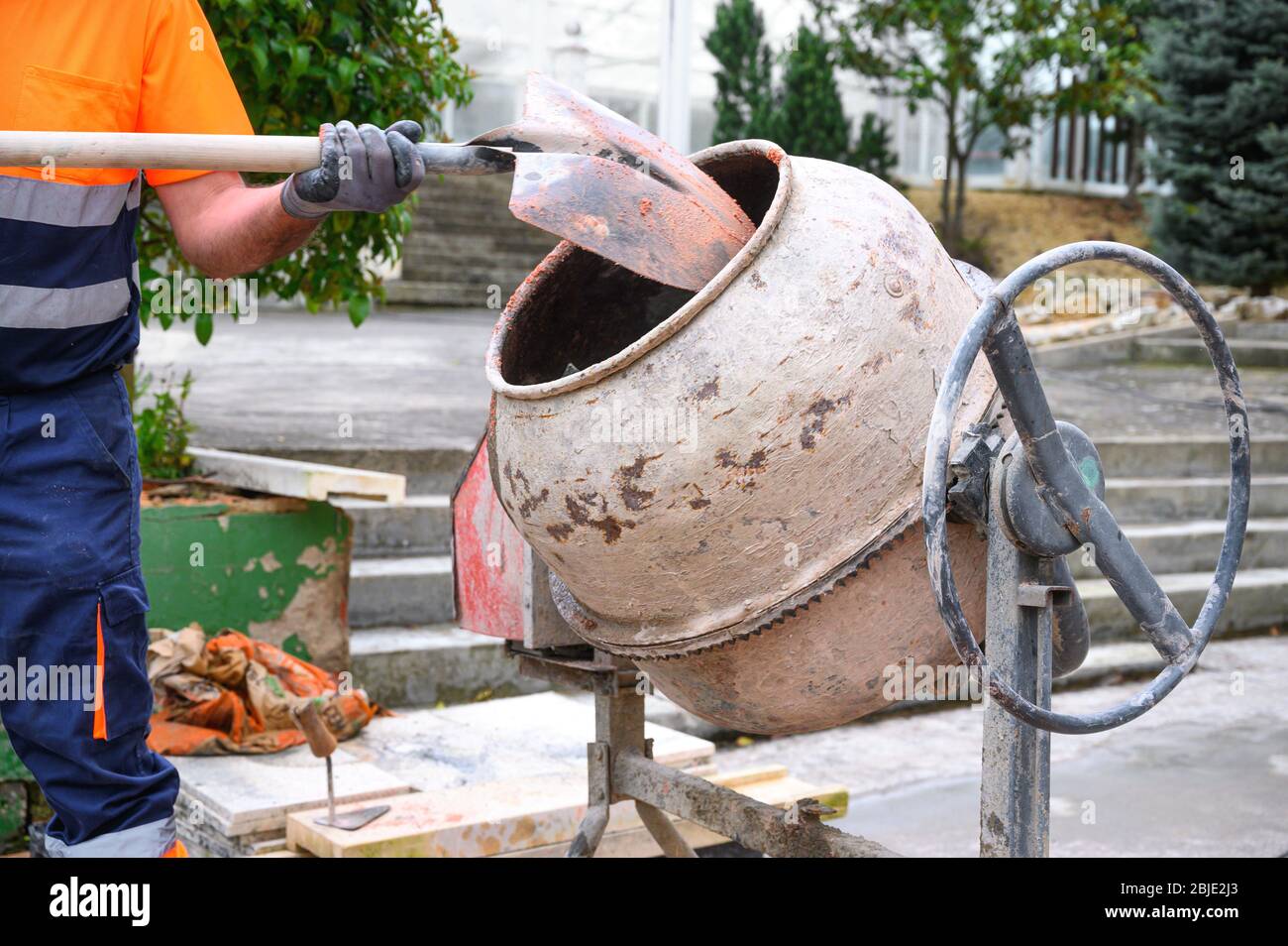 Travailleur de la construction non reconnaissable mettant du sable dans le  mixeur de béton avec une pelle Photo Stock - Alamy