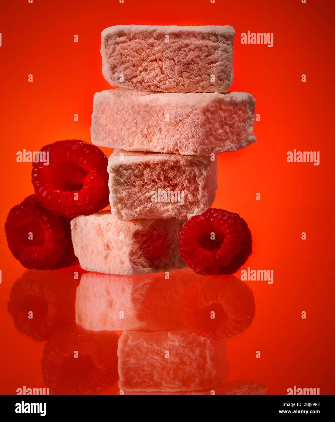 Des marshmallows de luxe à la framboise photographiés sur fond rouge dans le studio. Banque D'Images