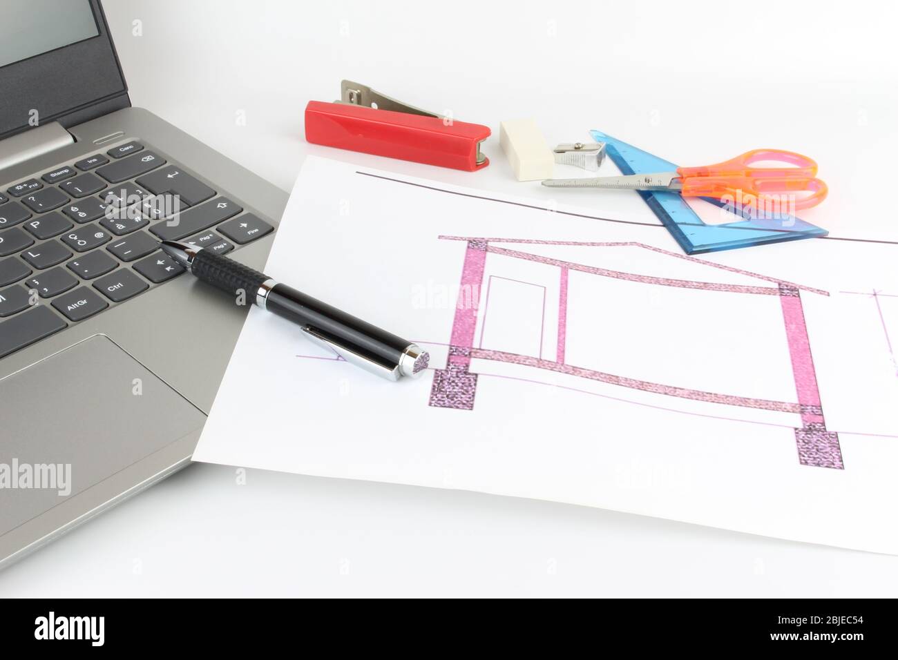 Studio design avec papeterie et ordinateur portable. Feuille de papier blanc imprimée avec un dessin de maison. Banque D'Images